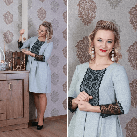 Model wearing the BETOLLI Lucky grey dress with black floral lace on the front and sleeve cuffs, a defined waist and pleated skirt.