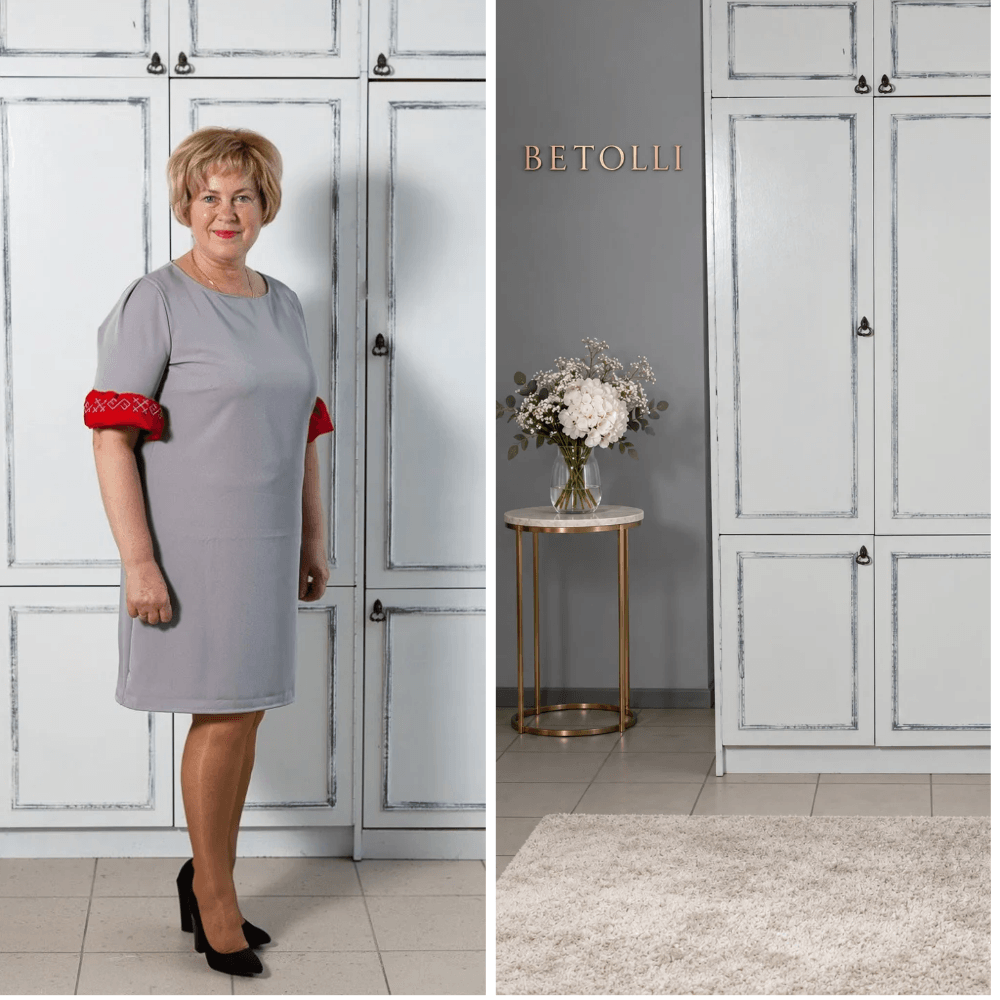 Model wearing the BETOLLI Māra grey dress with a round neckline and red ruffle sleeve cuffs embroidered with traditional Latvian symbols.