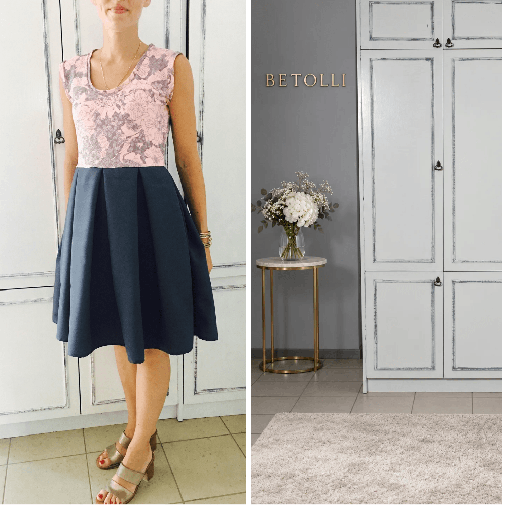 Model wearing the BETOLLI Puder sleeveless dress with a blush pink floral bodice, scoop neckline, defined waist and full navy pleated skirt.
